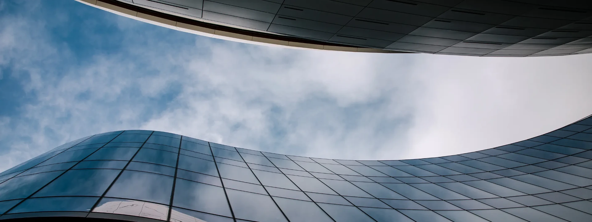 Curved glass facade of a modern building against a bright sky